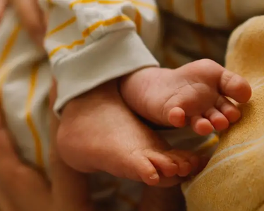 Nahaufnahmen Babyfüße in den Händen eines Erwachsenen